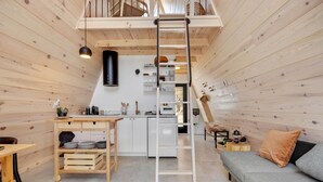 Ein gemütliches Blockhaus mit Schlafzimmer im Zwischengeschoss, einer Küche und einem Wohnbereich.