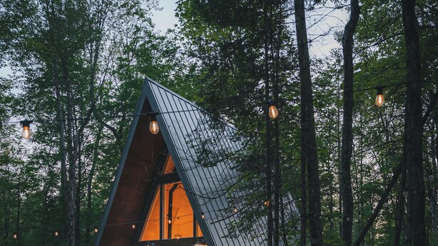 A cozy cabin with a triangular roof, a fire pit, and wooden chairs. - Prunella № 1, Prunella № 1 - A-Frame Cabin Getaway - Design, Comfort & Nature (Thorne)