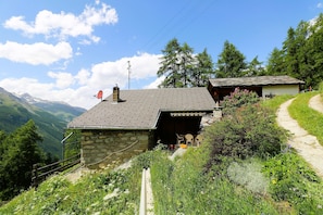 A stone house with a sloped roof, a satellite dish, and a small attached structure with a door. - Mayen Motau - Retour à l'essentiel | La Forclaz (La Forclaz)