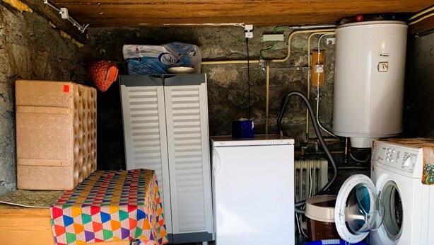 Une petite pièce utilitaire comprenant un lave-linge, un petit réfrigérateur, un radiateur et un panier à linge.