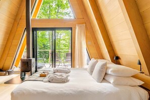Un dormitorio acogedor con paneles de madera, una cama grande, una chimenea y un ventanal corredero que da a un espacio al aire libre.