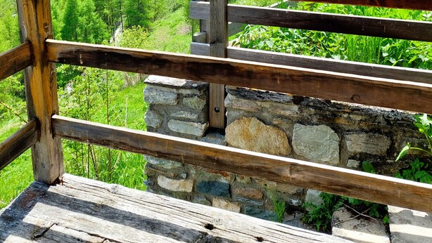 A mountain view with a wooden railing and stone wall. - Mayen Farquesses (Evolène)