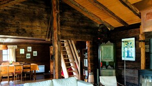A rustic cabin interior with a wooden ceiling, a sofa, a coffee table, a television, and a staircase. - Mayen Farquesses (Evolène)