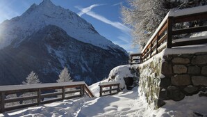 A snow-covered mountain landscape with a stone wall and wooden benches. - Mayen Farquesses (Evolène)