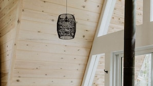 Une chambre mansardée chaleureuse, avec un plafond en pente, une grande fenêtre, un canapé, un plancher en bois et un poêle à bois.
