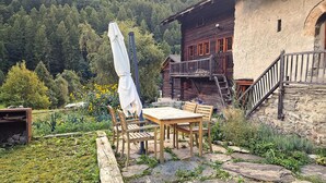A rustic wooden cabin with a balcony, surrounded by a garden with a table and chairs. - Chalet Berthé 11 (Les Haudères)