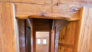 A wooden interior with a central wooden beam and a door at the end. - Chalet Berthé 11 (Les Haudères)