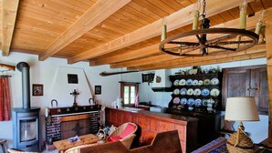 A rustic interior with a wooden ceiling, a stone fireplace, a woven sofa, and a patterned rug. - Chalet Tourbillon Gerber - La Sage (La Sage)