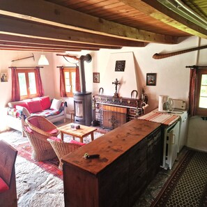 A cozy living room with a fireplace, a sofa, a coffee table, and a dining area with a wooden counter.