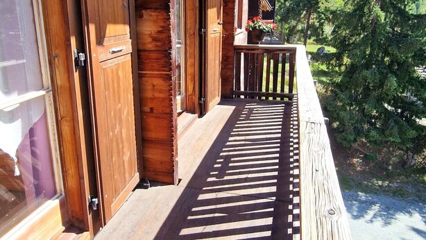 A wooden cabin with a porch overlooking a forested area. - Beau Séjour 2 (Evolène)