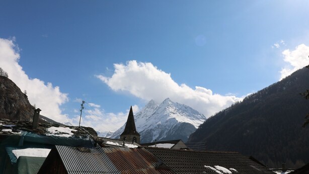 Paisaje montañoso con una iglesia y picos nevados.