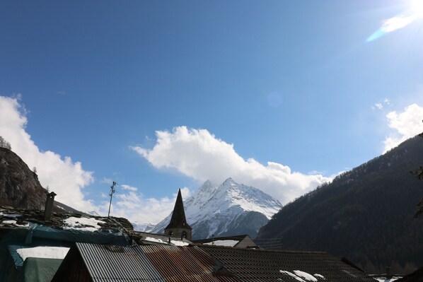 A mountain landscape with a church and snow-covered peaks.