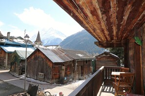 Un chalet rustique en bois doté d’un balcon, d’un vélo et surplombant un paysage montagneux.