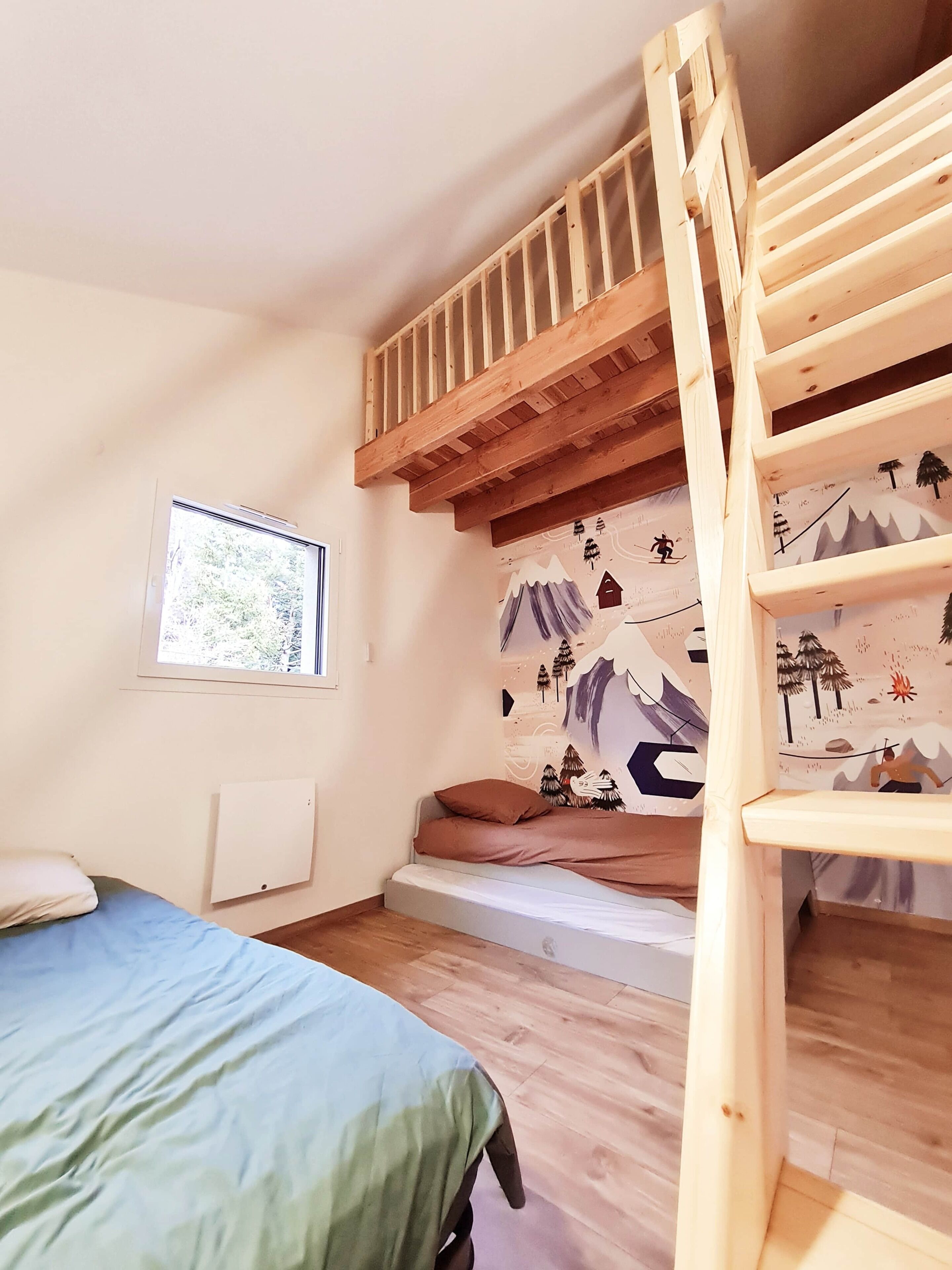 Quarto com beliche, janela e parede com mural de tema montanhista.