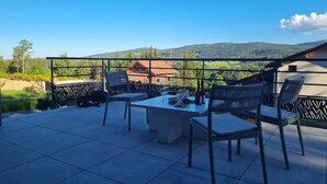 An outdoor patio with a table and chairs, a view of a mountain, and a building in the background. - Le Perchoir de l'Olme (Chalmazel-Jeansagniere)