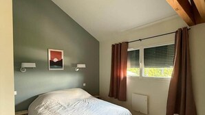 A bedroom with a bed, a window with curtains, a wall-mounted lamp, and a picture. - Le Perchoir de l'Olme (Chalmazel-Jeansagniere)