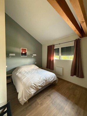 Un dormitorio con cama, una ventana con cortinas, una lámpara de pared e imagen.