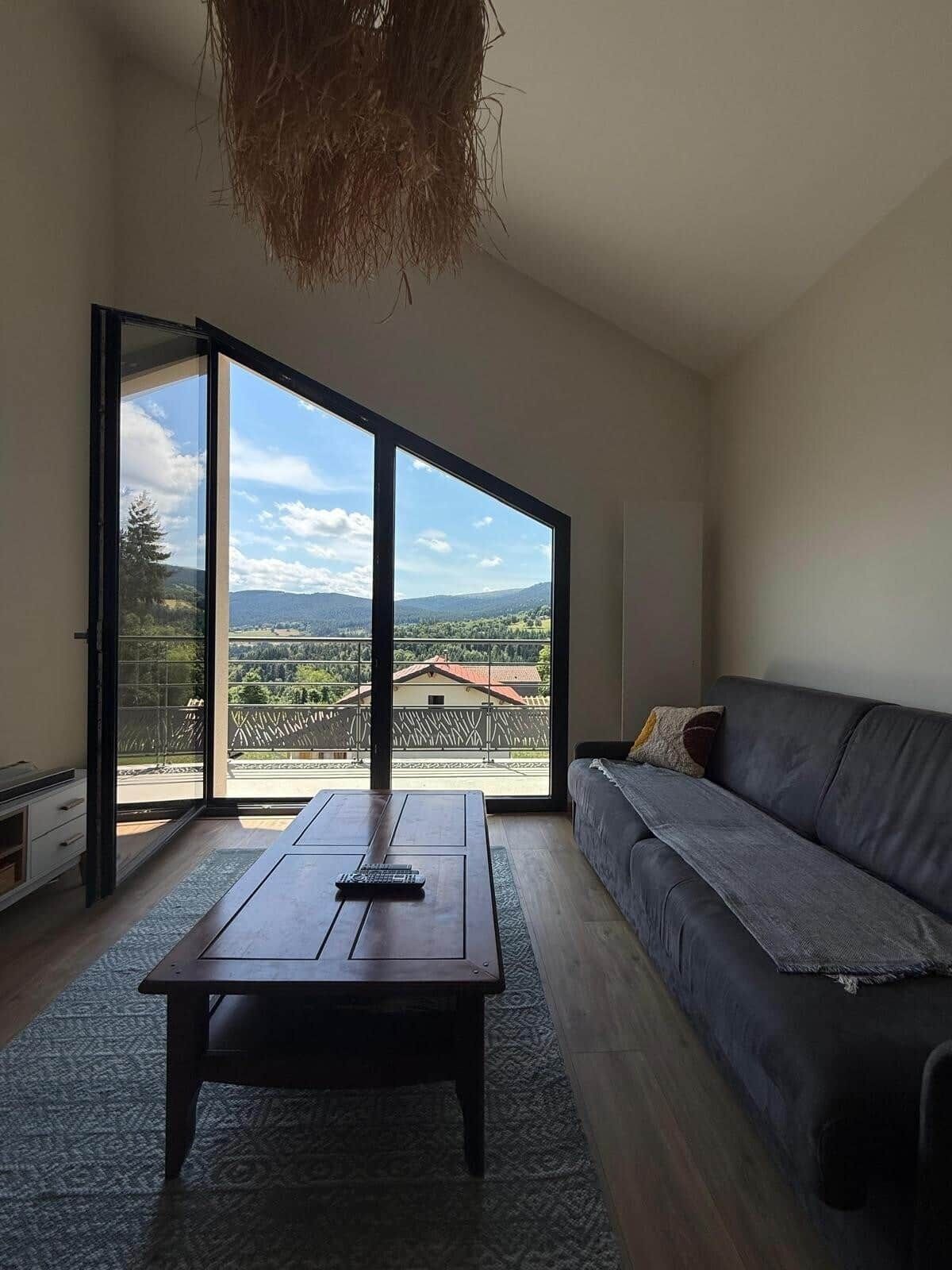 Amplia habitación con sofá, una mesita de centro y vistas al exterior a través de amplios ventanales.