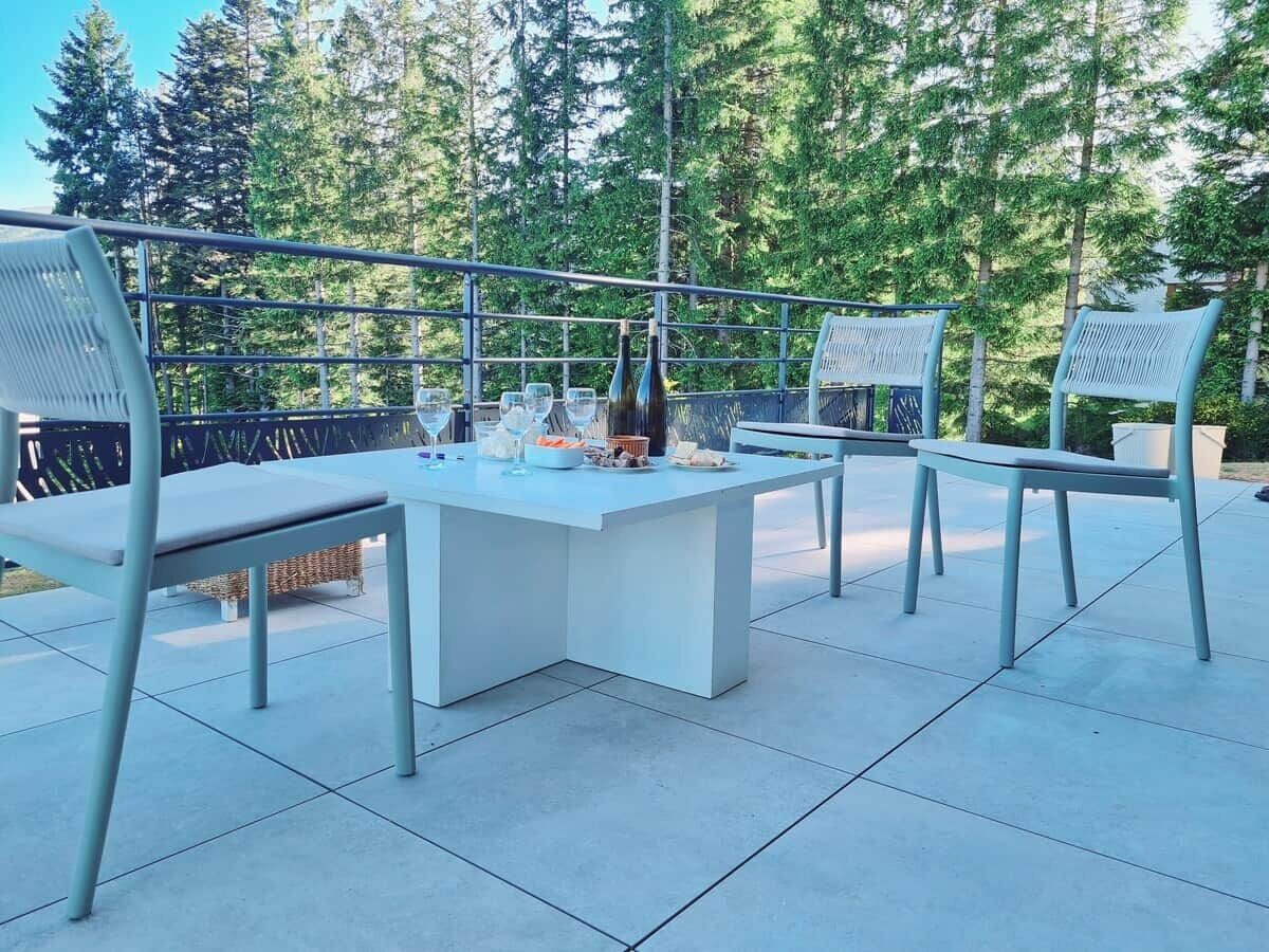 Eine Außenpatio mit einem weißen Tisch und Metallstühlen, umgeben von einem Metallgeländer.