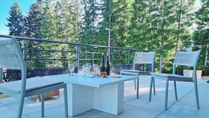 An outdoor patio with a white table and metal chairs, surrounded by a metal railing. - Le Perchoir de l'Olme (Chalmazel-Jeansagniere)