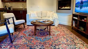 Una sala de estar moderna con un sofá, sillones, una mesa de centro, una chimenea y un televisor.
