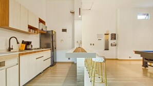 A modern kitchen with wooden cabinets, a built-in stove, and a bar area with stools.