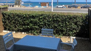 A patio with a table and chairs, a street lamp, and a view of the beach and ocean.