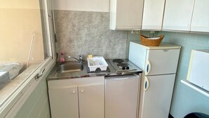 A compact kitchen with a sink, stove, and white cabinets.