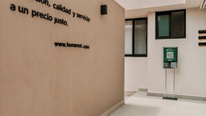 Fachada de un edificio con un cartel que anuncia la ubicación, la calidad y el servicio a un precio justo.