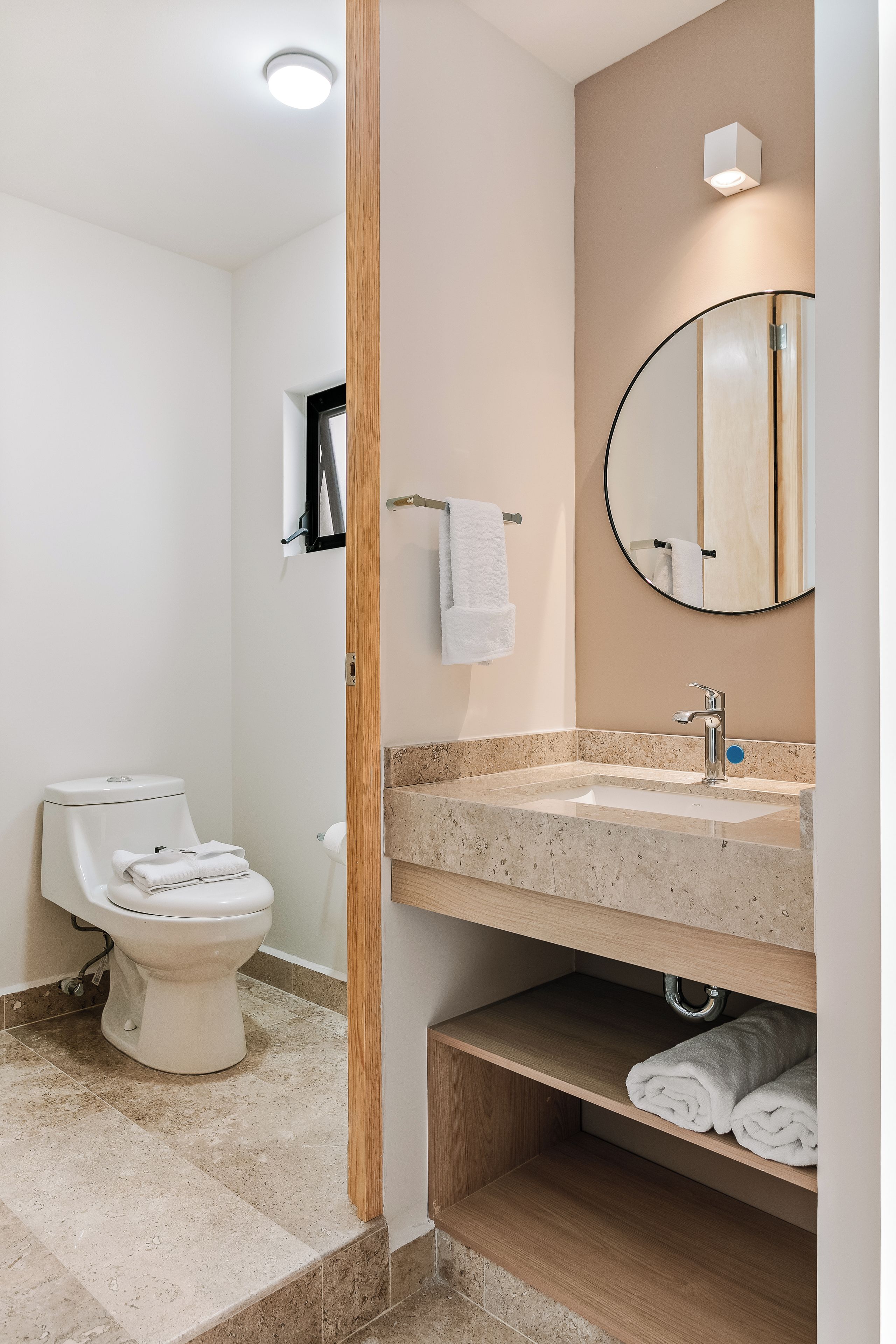 A modern bathroom with a toilet, sink, mirror, and towel rack.