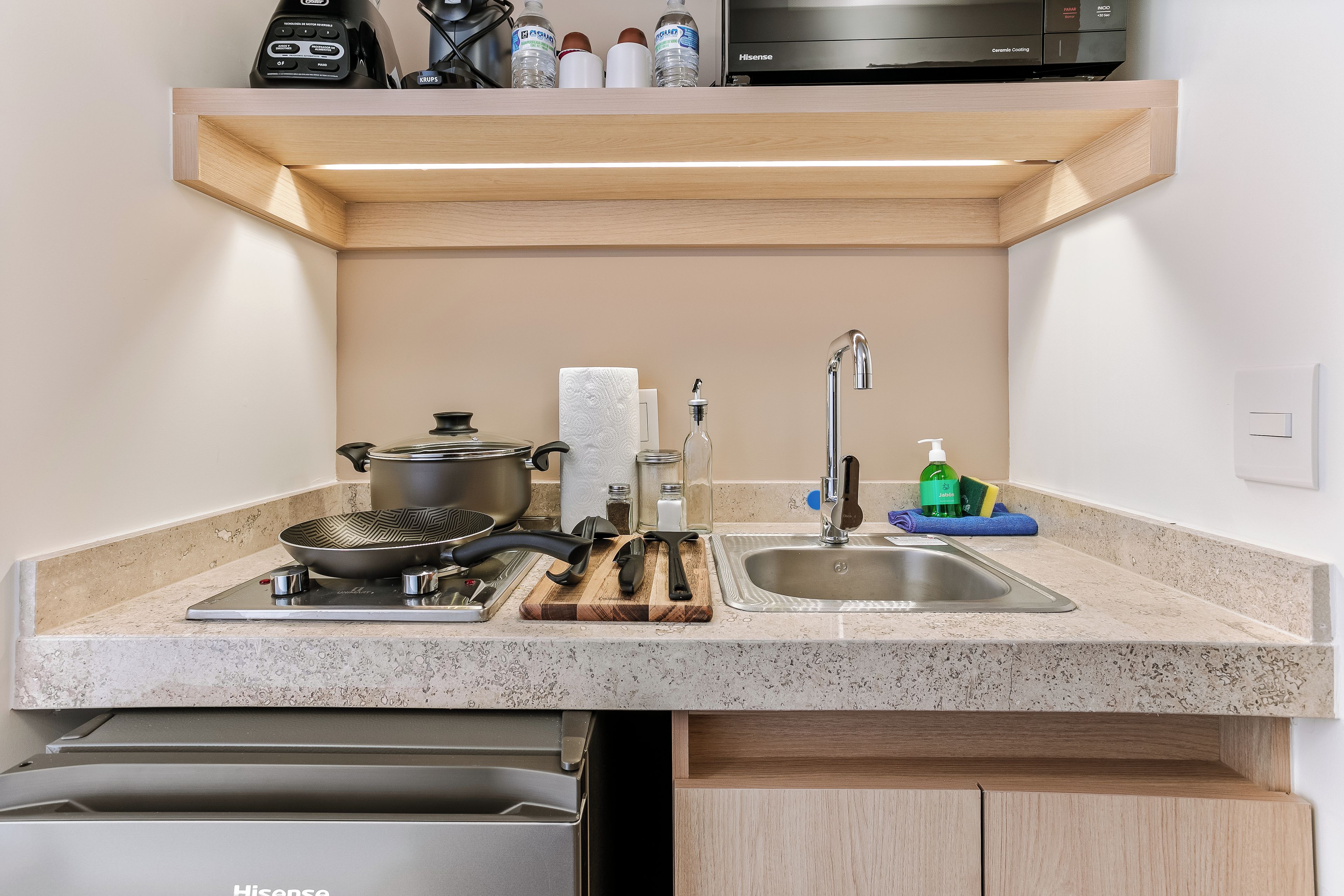 Una cocina moderna con lavavajillas integrado, estufa, pileta y microondas sobre la encimera.