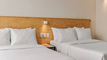 A hotel room with two beds, a wooden headboard, a ceiling fan, and a wall-mounted light fixture.