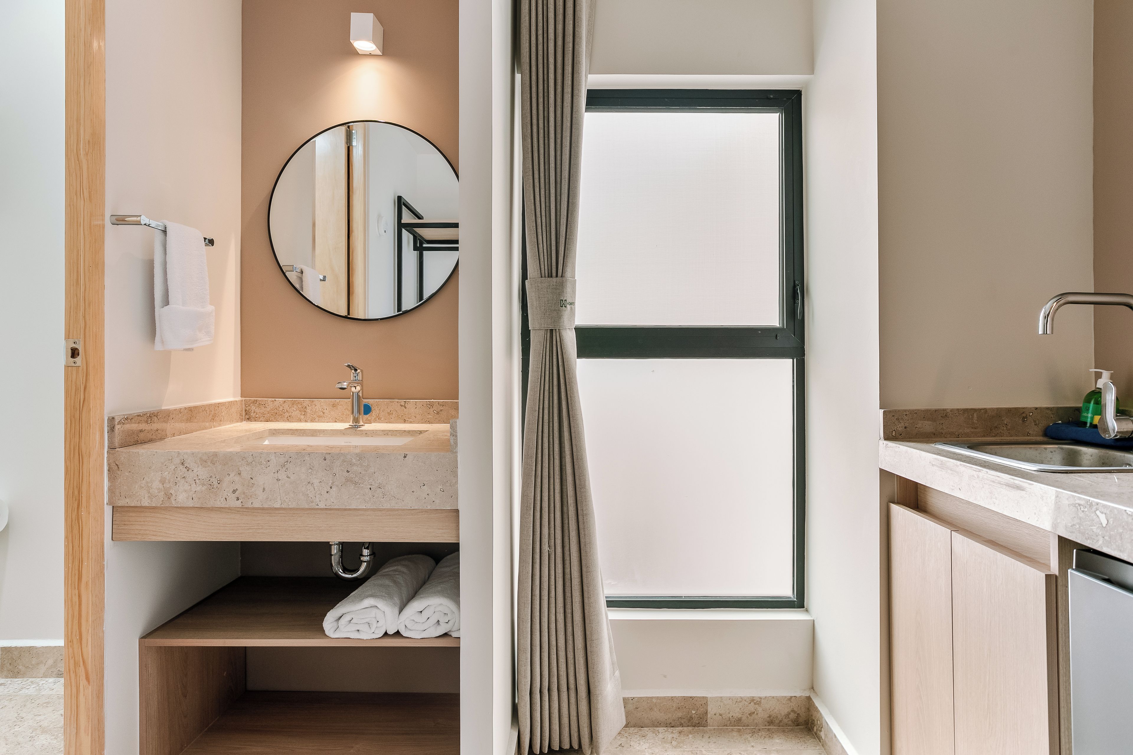 A modern bathroom with a round mirror, a sink, and a shower area.