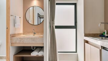A modern bathroom with a round mirror, a sink, and a shower area.