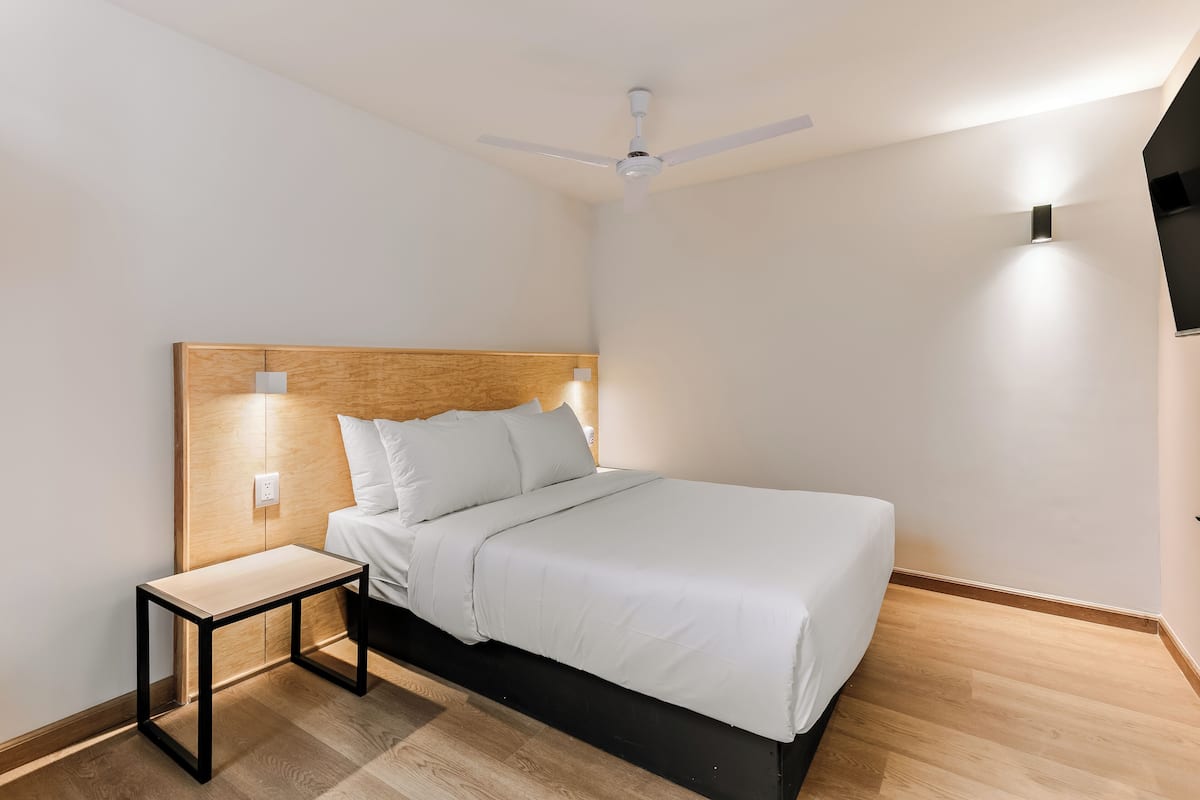 A neatly arranged bedroom with a bed, bedside table, and a ceiling fan.