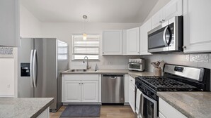A modern kitchen with white cabinets, stainless steel appliances, a built-in microwave, and a gas stove. - Charming 3-bedroom house with fast WiFi and AC in fabulous Spring (Spring)