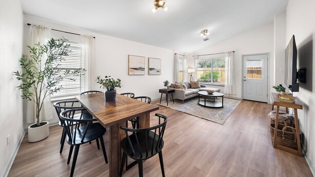A spacious living area with a wooden dining table, black chairs, a sofa, and a TV mounted on the wall. - Charming 3-bedroom house with fast WiFi and AC in fabulous Spring (Spring)