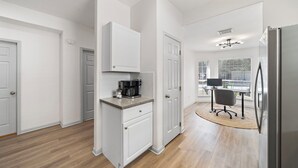 A modern kitchen with white cabinetry, a built-in coffee maker, and a dining area with a computer and chair. - Charming 3-bedroom house with fast WiFi and AC in fabulous Spring (Spring)