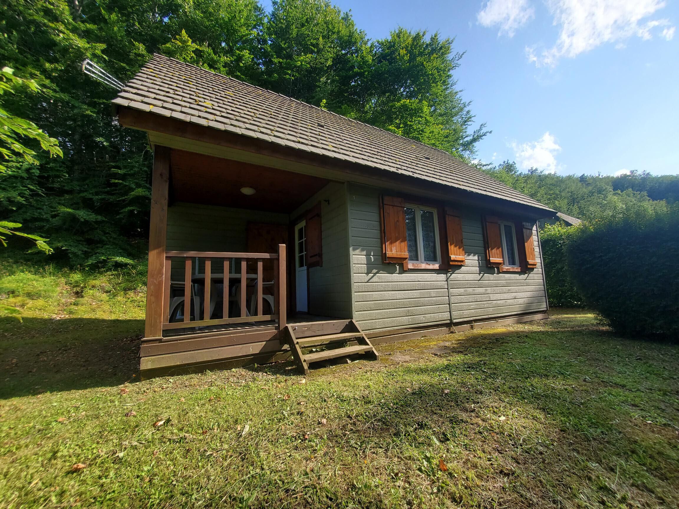 A small wooden cabin with a porch and a set of stairs leading to the entrance.