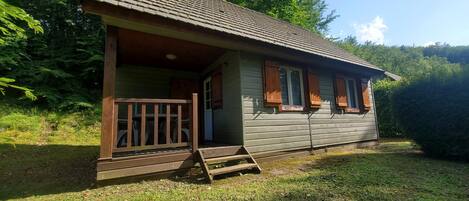 A small wooden cabin with a porch and a set of stairs leading to the entrance.