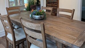 A dining room with a large wooden table, six chairs, a chandelier, and a deer head mirror. - Charming Vintage Retreat in the Heart of Anaconda. (Anaconda)