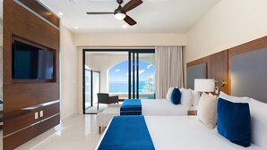 Habitación de hotel con una cama grande, televisión, ventilador de techo y vista al mar.