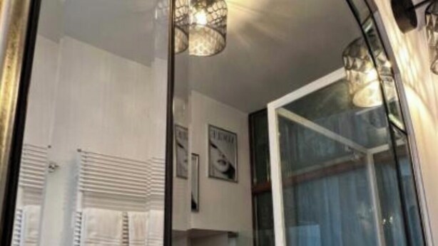 A bathroom with a glass shower door, a towel rack with white towels, and a wall-mounted light fixture. - Calefati Gallery Luxury Apartment  (Bari)