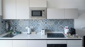 Een moderne keuken met een magnetron, broodrooster, waterkoker en koffiezetapparaat op het aanrecht.