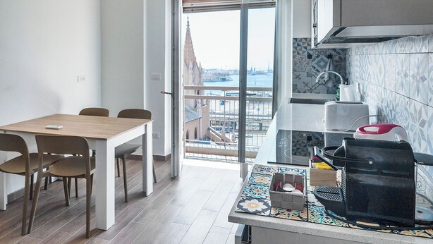 Een moderne keuken met uitzicht op een stadsgezicht door een glazen deur.