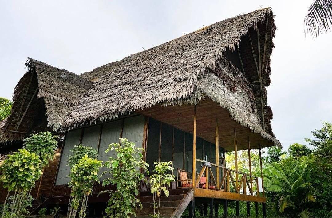 A traditional thatched-roof building with a wooden balcony and hanging plants.