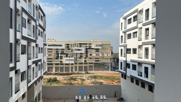 A modern building with multiple floors, a courtyard with a pool, and outdoor seating areas. - Very nice apartment for rent in kenitra with swimming pool and gym (Kénitra)