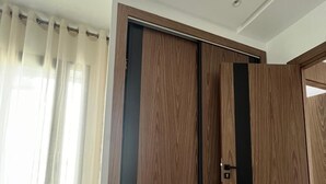 A modern room with a wooden wardrobe, a fluffy stool, and a large window with sheer curtains. - Very nice apartment for rent in kenitra with swimming pool and gym (Kénitra)