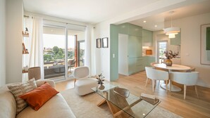 A modern living room with a sofa, coffee table, and dining area with chairs. - An amazing apartment with Ocean and Estoril view (Cascais)