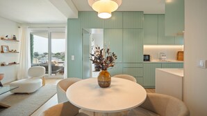 A modern living room with a round table, a vase with branches, and a view through a glass door. - An amazing apartment with Ocean and Estoril view (Cascais)
